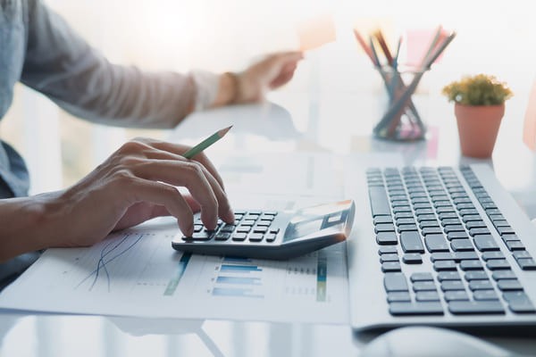 Person typing on a calculator on a desk