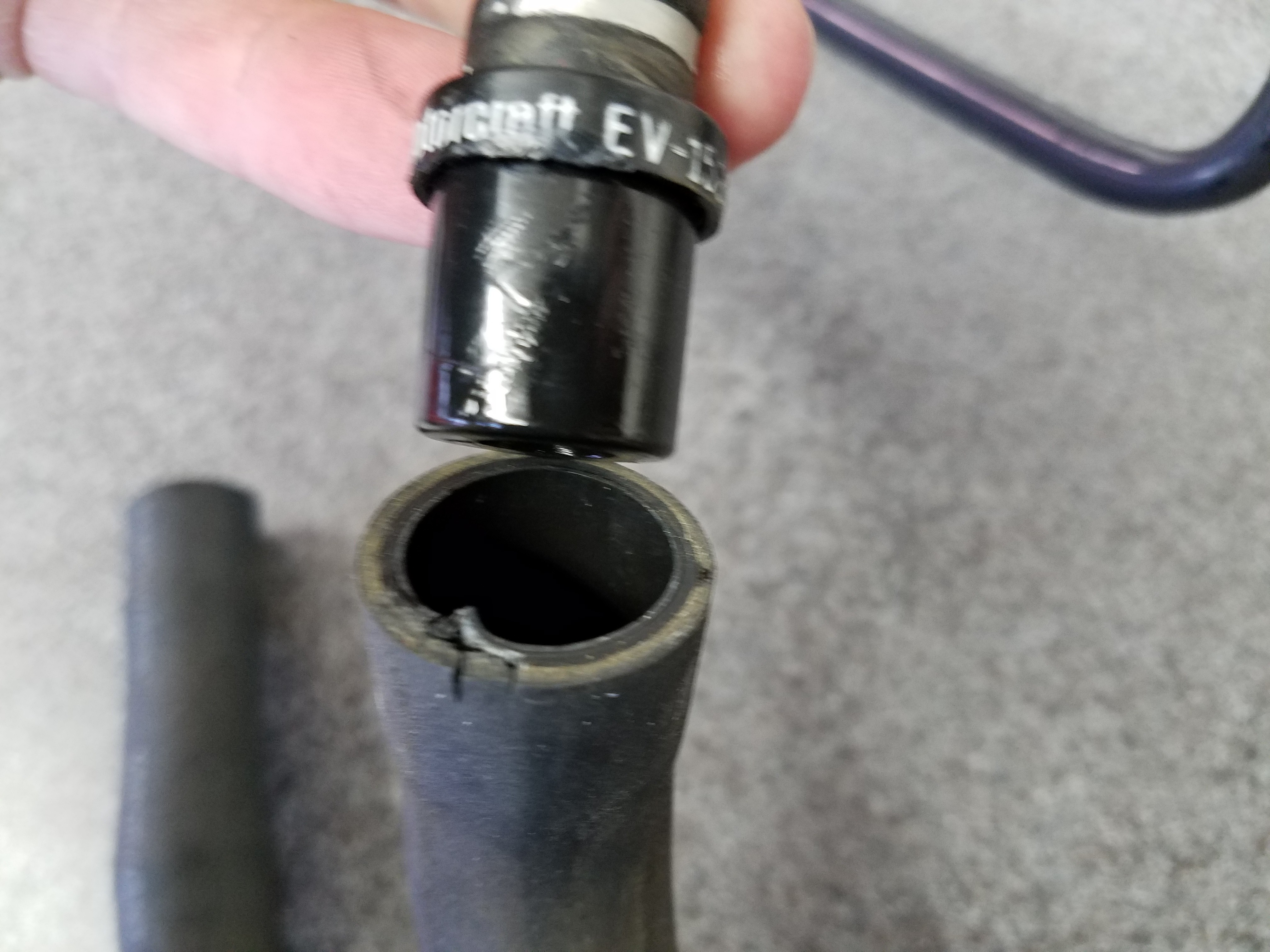 Damaged lower vacuum hose for a PCV valve in an Aston Martin DB9, illustrating the curved, molded design