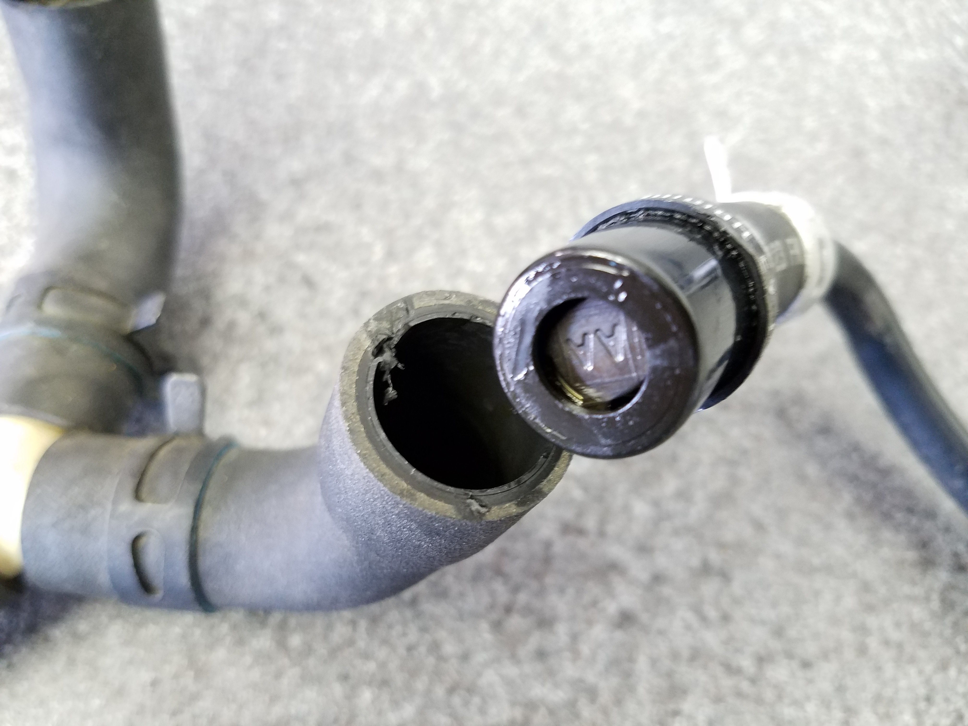 Another example of a damaged lower vacuum hose for a PCV valve in an Aston Martin DB9, showing the impact of heat and age