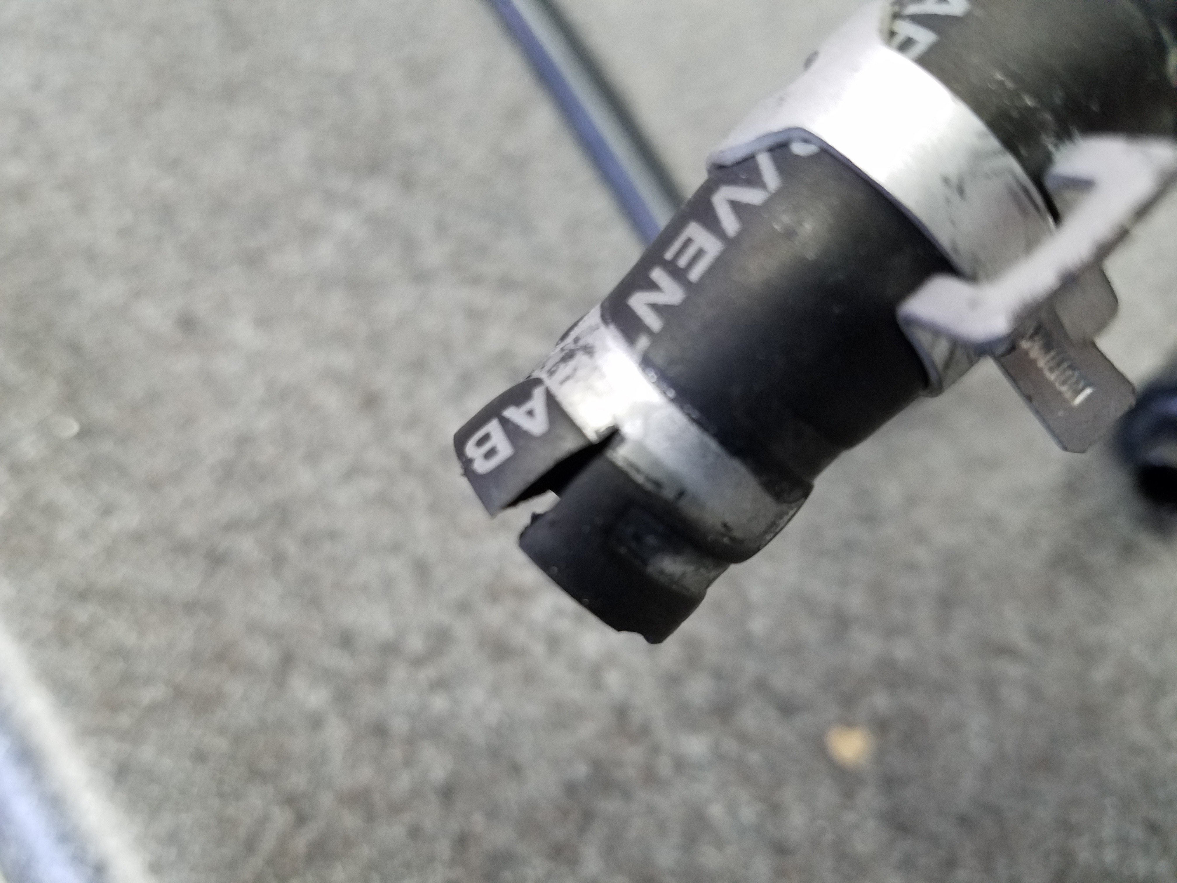 Damaged upper vacuum hose for PCV valve in an Aston Martin DB9, showing a tear caused during removal