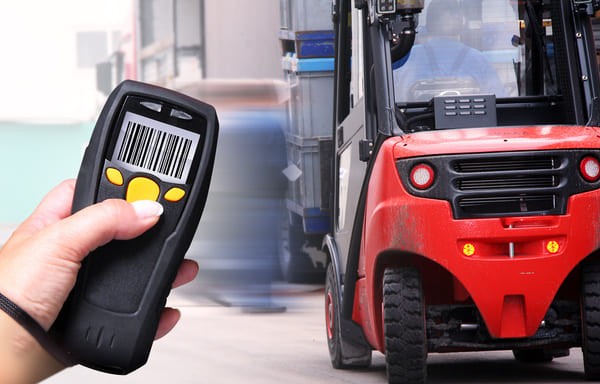 Hand holding an RF scanner pointed at a forklift
