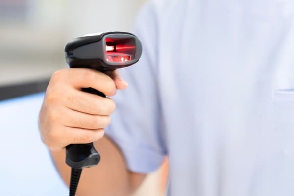 Person holding a handheld RF scanner with a red light projecting out