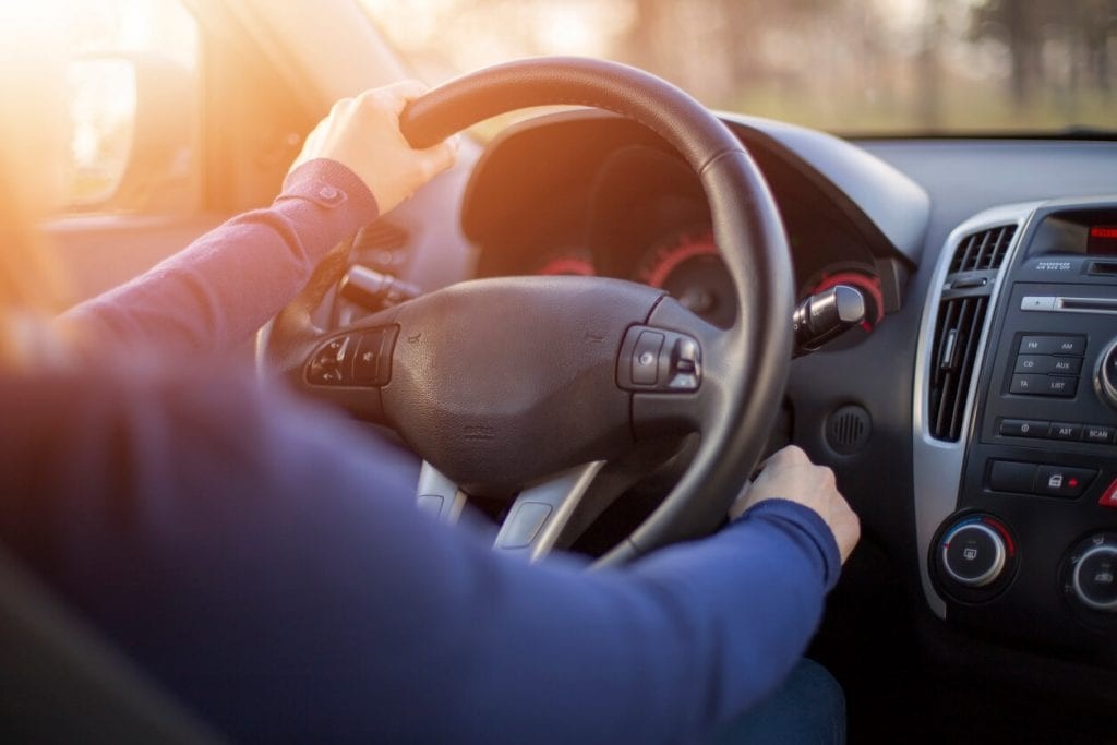 Hand on a steering wheel of a car indicating potential engine issues