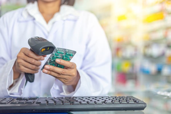Pharmacist using a handheld RF scanner to scan a package of pills