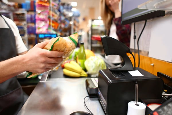 Grocery store worker ringing up an item using a presentation RF scanner