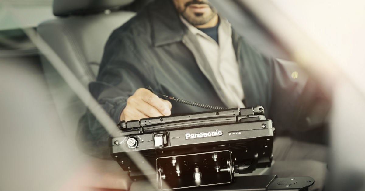 Technician using Panasonic Toughbook for diagnostics in a garage